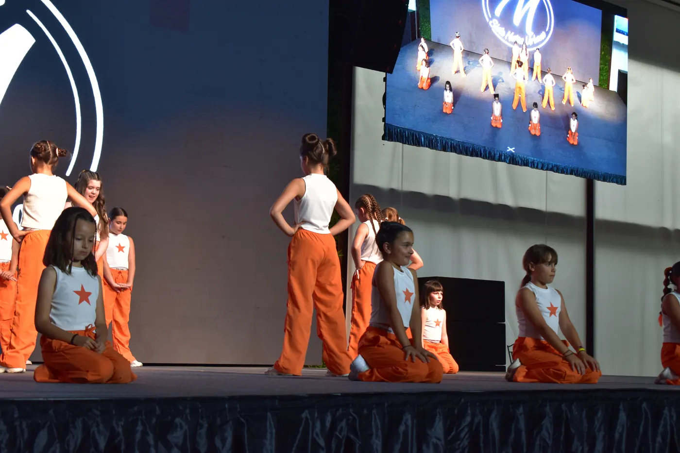 Grupo infantil de danza urbana con estrella naranja actuando en Siete Notas